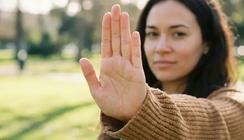 Primer plano de una persona haciendo un gesto firme de 'stop' con la mano, transmitiendo seguridad y calma